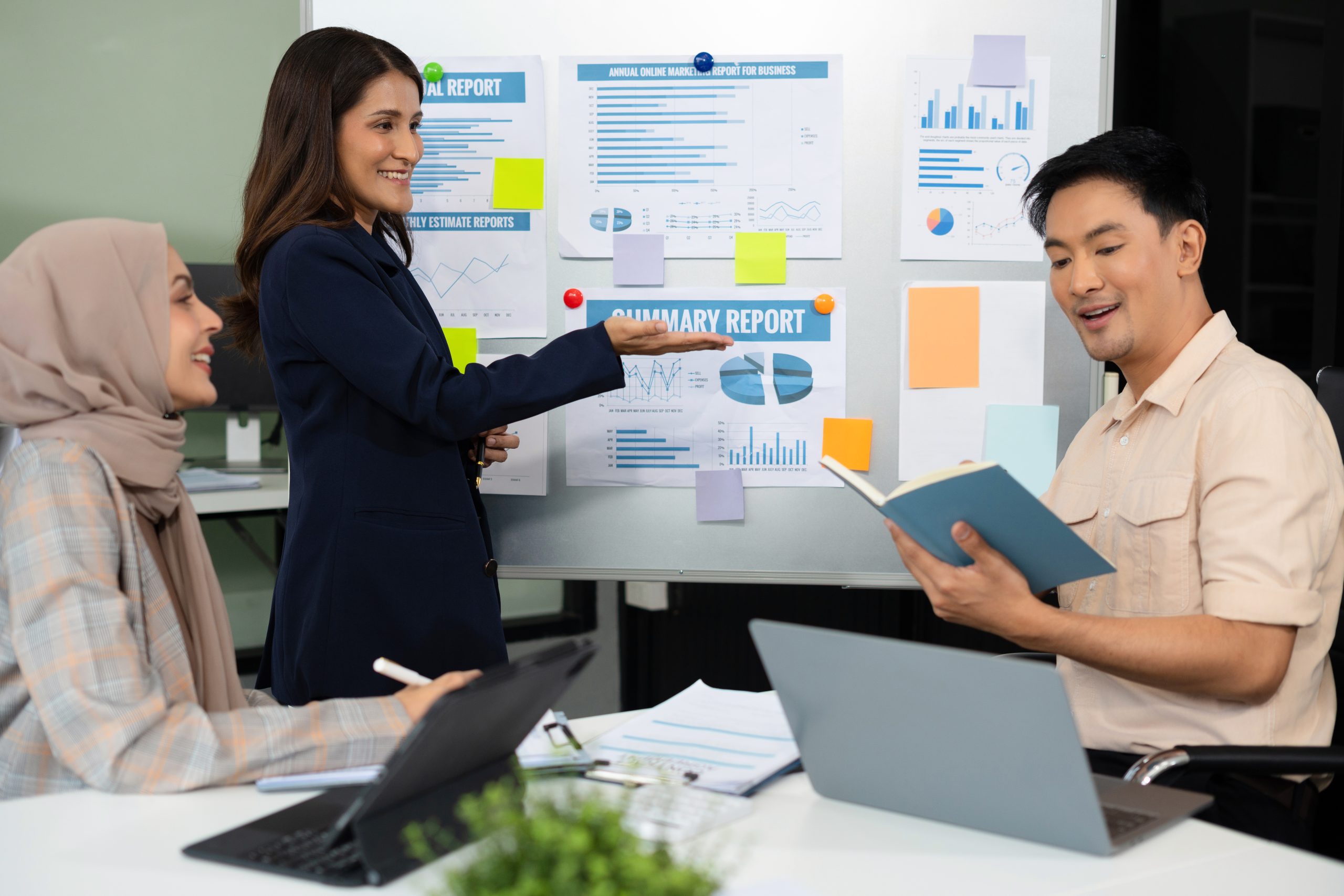 3 orang diskusi di depan laptop,icon digital di sekitar